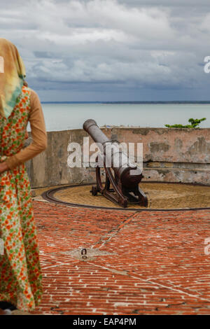 A local woman examines a cannon at Fort Marlborough, a 18th English century fort located in Bengkulu City, Sumatra. Stock Photo