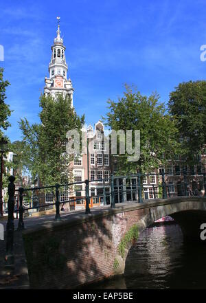 17th century Zuiderkerk church tower at the corner of Raamgracht and  Groenburgwal canal in summer with tall trees. Stock Photo