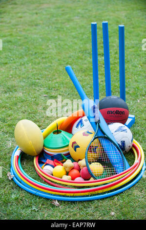 Brightly coloured plastic children's sports equipment with cricket bats, balls, tennis raquet and hoops on a coaching course Stock Photo