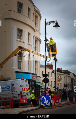 Workman on cherry picker lift maintaining street light Stock Photo