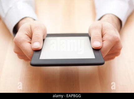 Tablet or e-book reader in hands on wood background Stock Photo