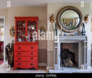 George III period mahogany secretaire painted in a red mixed by Farrow & Ball by stone fireplace Stock Photo