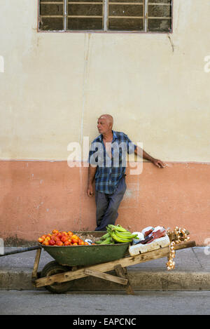 MATANZAS, CUBA - MAY 10, 2014: Fruit peddler waits for customers on the shady side of the street Stock Photo