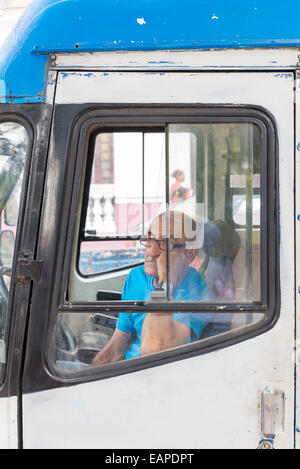 MATANZAS, CUBA - MAY 10, 2014:  An old bus driver waits for passengers in the main square of the colonial city of Matanzas Stock Photo