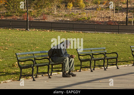 Solitary African American man deep in thought on a bench in Prospect Park, Brooklyn, NY. Stock Photo