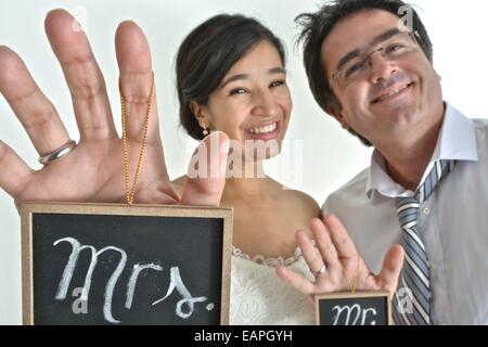 Newly wed hispanic couple holding signs saying " Mr" and " Mrs" in their hands. Stock Photo