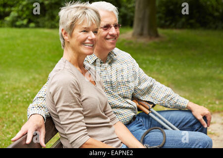 Happy senior couple sitting on a park bench in summer Stock Photo