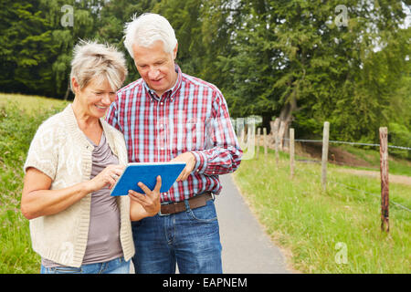 Senor couple navigating with tablet computer while hiking in nature Stock Photo