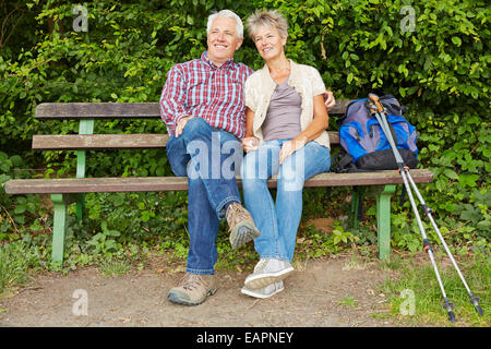 Senior couple taking break on bench while hiking in nature Stock Photo