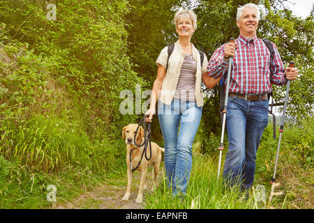 Smiling senior couple with dog on a hike in a forest