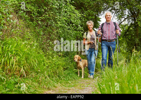 Happy senior couple walking with dog on a hiking trail