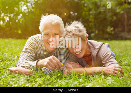 Happy senior couple laying in meadow in the grass in summer Stock Photo