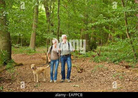Happy senior couple waking the dog in a forest in summer