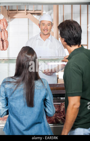 Couple Buying Meat From Butcher Shop Stock Photo