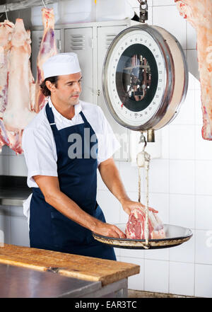 Butcher Weighing Meat On Scale Stock Photo