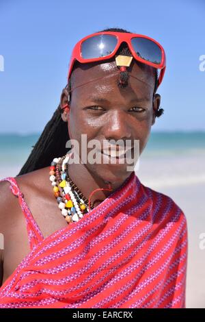 Young Maasai man wearing traditional dress and sunglasses on the beach, Dongwe Beach, Dongwe, Zanzibar, Tanzania Stock Photo