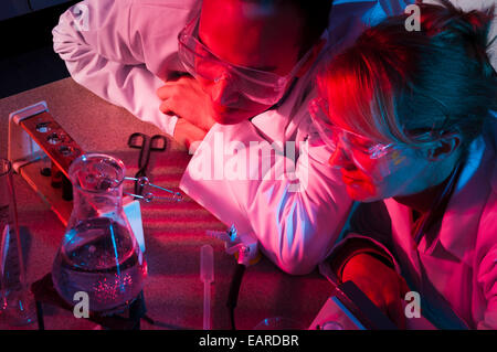 Woman and man in lab coats with lab equipment red and blue light Stock Photo