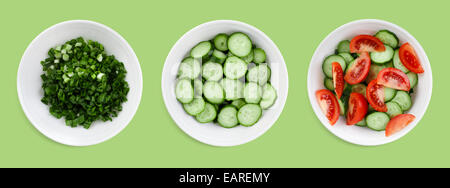 Fresh tomatoes, cucumbers and green onions chopped salad on a green background. Clipping path. Stock Photo