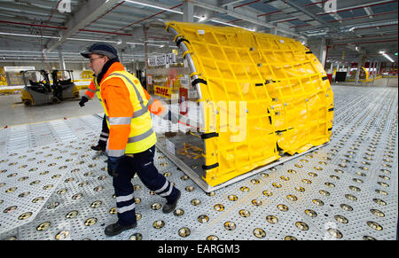 Schkeuditz, Germany. 20th Nov, 2014. A staff member of DHL, a division of the German logistics company 'Deutsche Post DHL', pulls on a freight container at the Leipzig/Halle airport in Schkeuditz, Germany, 20 November 2014. DHL has started running a 40.000 square metre sorting system at the airport, increasing its capacity by more than 50 percent to 150.000 delivers per hour, a move that came along with the expansion of the airport's capacity. Photo: Peter Endig/dpa/Alamy Live News Stock Photo