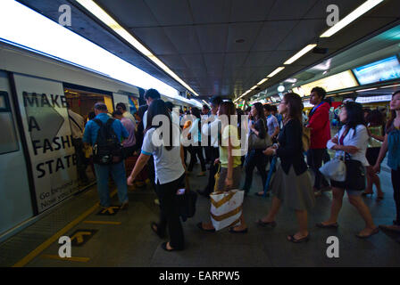 Rush hour commuters board a train from a crowded station platform. Stock Photo