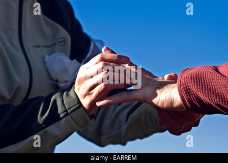 A groom places a wedding band on a finger of his bride in Antarctica. Stock Photo