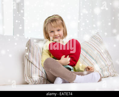 smiling girl with big red heart sitting on sofa