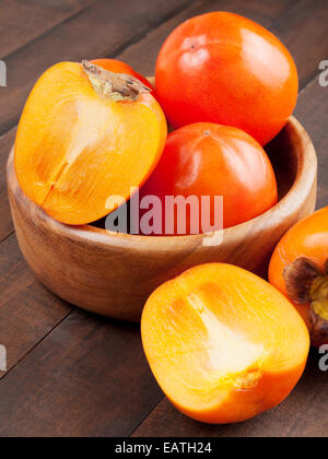 persimmons in bowl on wooden table