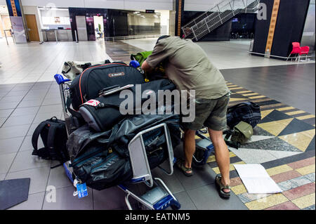 A dejected man waits with his luggage after missing the last flight. Stock Photo