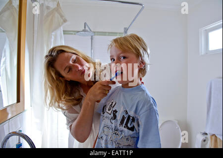 A mother brushes her sons teeth for his first day of school. Stock Photo