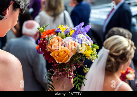 A bridesmaid holds a brides bouquet at a Greek Orthodox wedding. Stock Photo