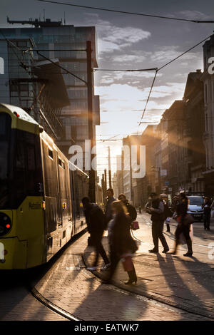Manchester, Low evening winter sun in Fountain street, near Piccadilly Gardens, Shoppers silhouetted against the sun producing long shadows crossing the road as they enjoy a fine sunny end to the day in Manchester. Manchester Metrolink city centre tram lines & route. Stock Photo