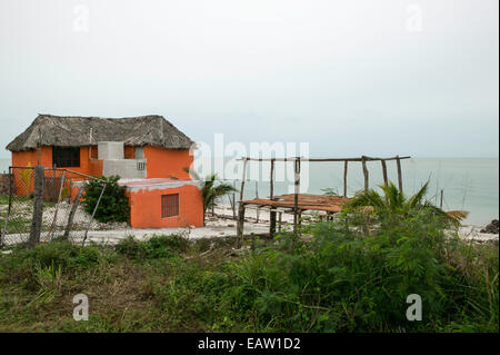 Mexican waterfront house with traditional thatched roof and orange painted stucco walls. Stock Photo