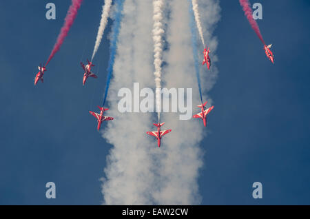 Seven RAF Red Arrows perform an acrobatic maneuver in formation with red white and blue smoke at the 2014 Southport Airshow Stock Photo