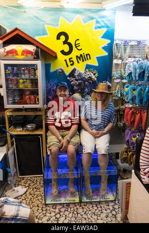 Nam Nam fish therapy tanks with  doctor fish in tanks and two tourists taking 15 mins for three euros Stock Photo