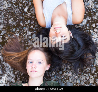 Two teenage girl friends lying on a granite background, top view close-up. Stock Photo