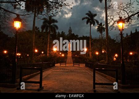 Street lights illuminate a statue in Havana's Plaza de Armas. Stock Photo