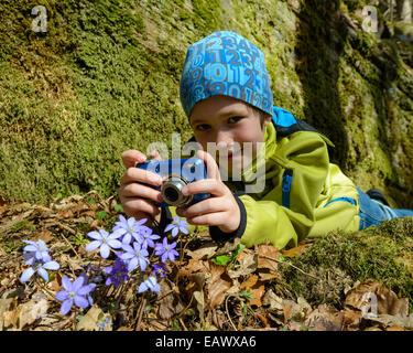 Young boy smiles while holding a blue digital camera Stock Photo