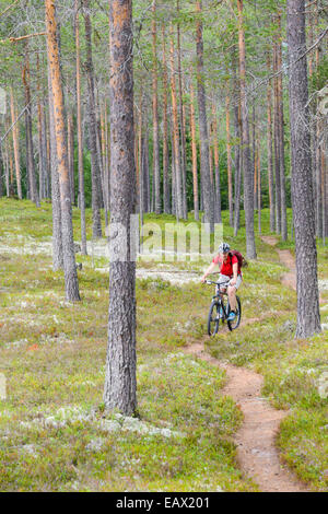 Woman riding her bike down a forest path Stock Photo