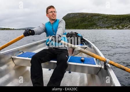 Rower in a blue life jacket rowing on a lake Stock Photo