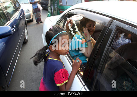 Dhaka November 2014. A child on the side of the road attempts to sell flowers to passing commuters in cars and buses. Stock Photo