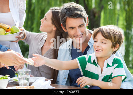 Family eating healthy meal together outdoors, father holding son on lap Stock Photo