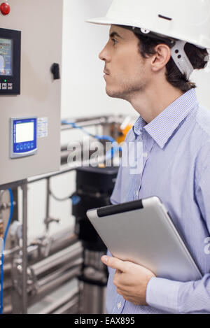 Technician checking industrial equipment in operation at plant Stock Photo