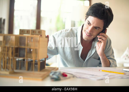 Architect talking on cell phone at desk Stock Photo
