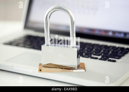 Padlock and credit card sitting on top of laptop computer Stock Photo