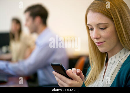 Young woman using smartphone in office Stock Photo