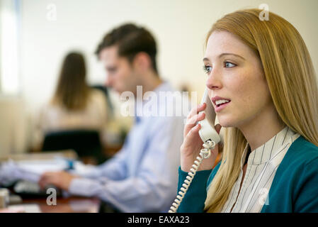 Woman using landline phone in office Stock Photo