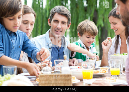 Family eating together at outdoor gathering Stock Photo