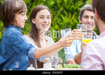 Family clinking glasses at outdoor gathering Stock Photo