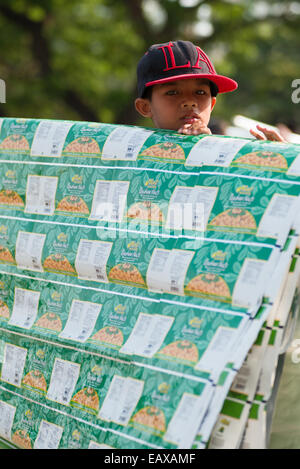 Young Thai boy selling paper sheets at the anti government demonstrators site at Lumpini Park, Bangkok, Thailand. Stock Photo