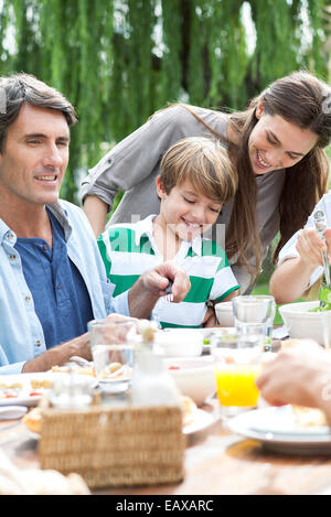 Family eating together at outdoor gathering Stock Photo